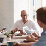 Group of professionals engaged in a brainstorming session around a table in a contemporary office space.