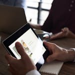 Professionals in a meeting, using a tablet for digital presentation and notes.